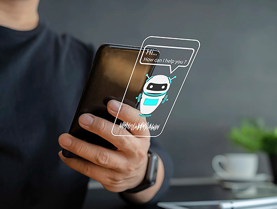 A hand holding a phone that has a talking robot character AI assistant on it. Credit: iStock