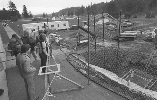 People stand on the walkway next to Environmental Studies building looking at the building site.