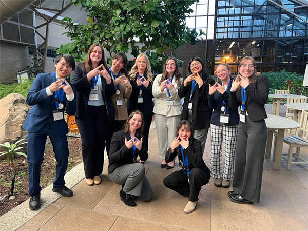 A group of students make the DECA Diamond symbol with their hands