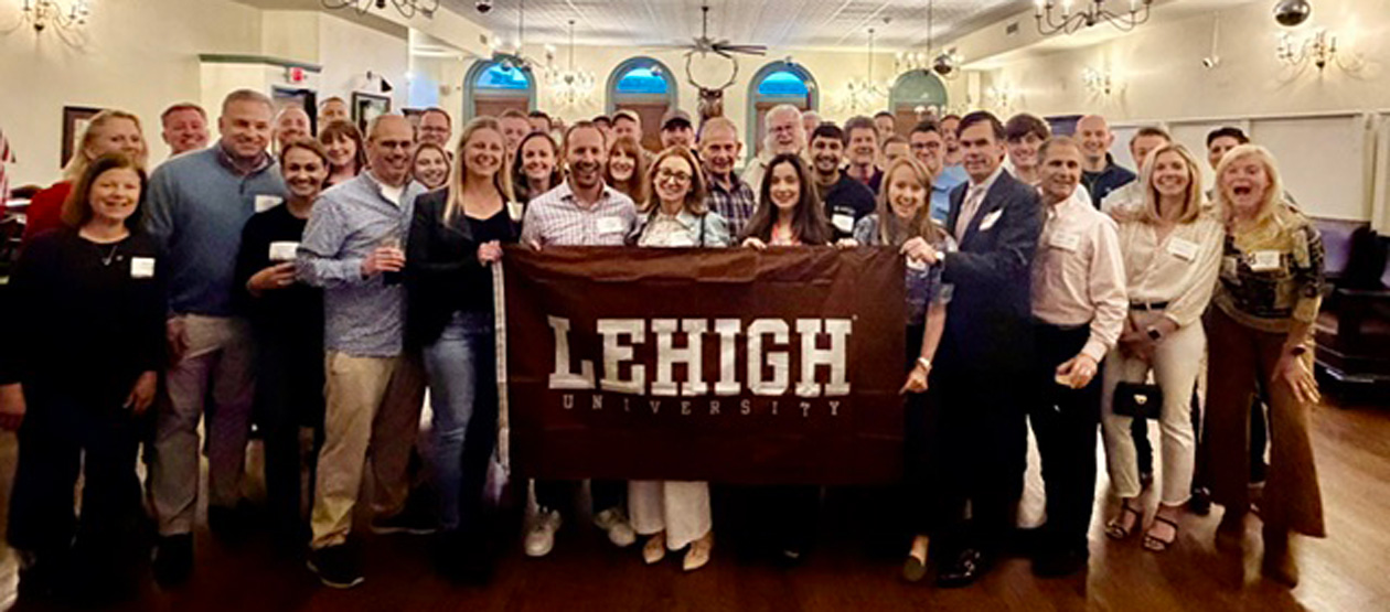 a gathering of Lehigh alumni with a "Lehigh University" banner in the center of the photo a gathering of Lehigh alumni with a "Lehigh University" banner in the center of the photo