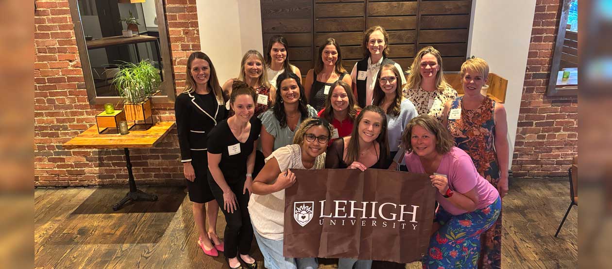 a group of women gather around a Lehigh banner for a group photo