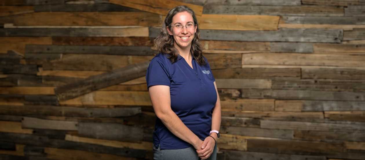 Rebecca Merola poses in front of a wood planked wall
