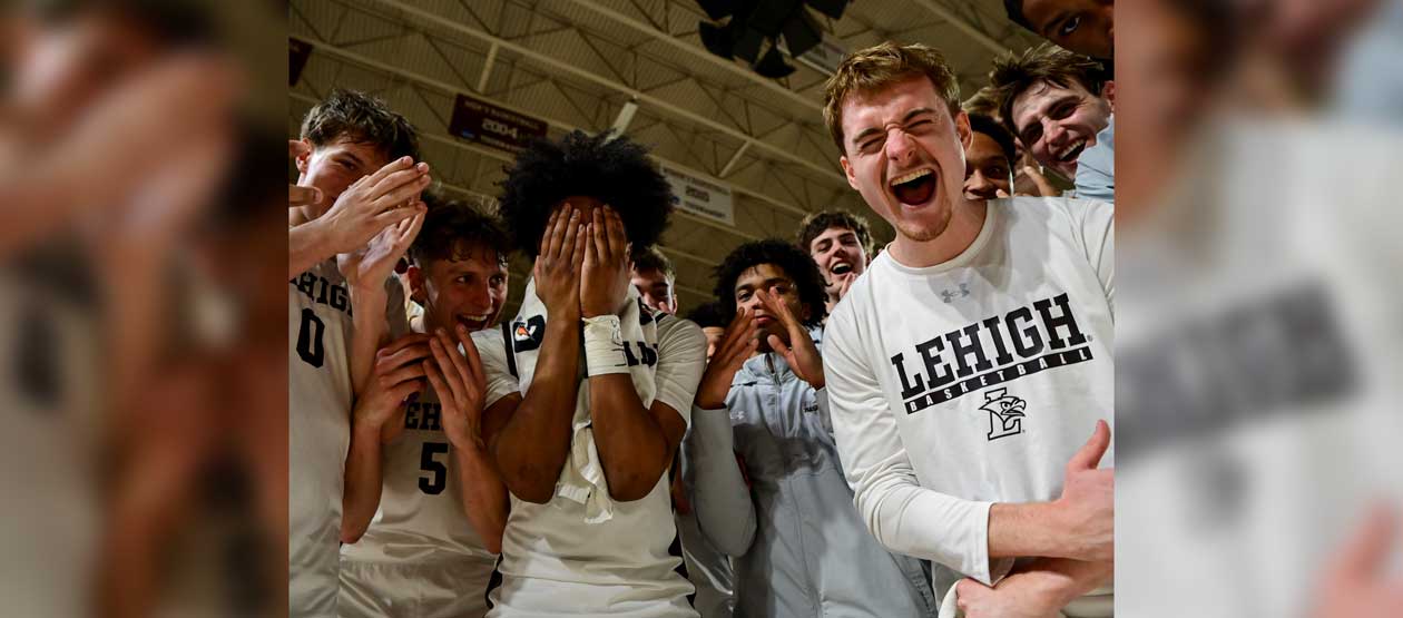 Men's Basketball team gathered around for a celebratory huddle