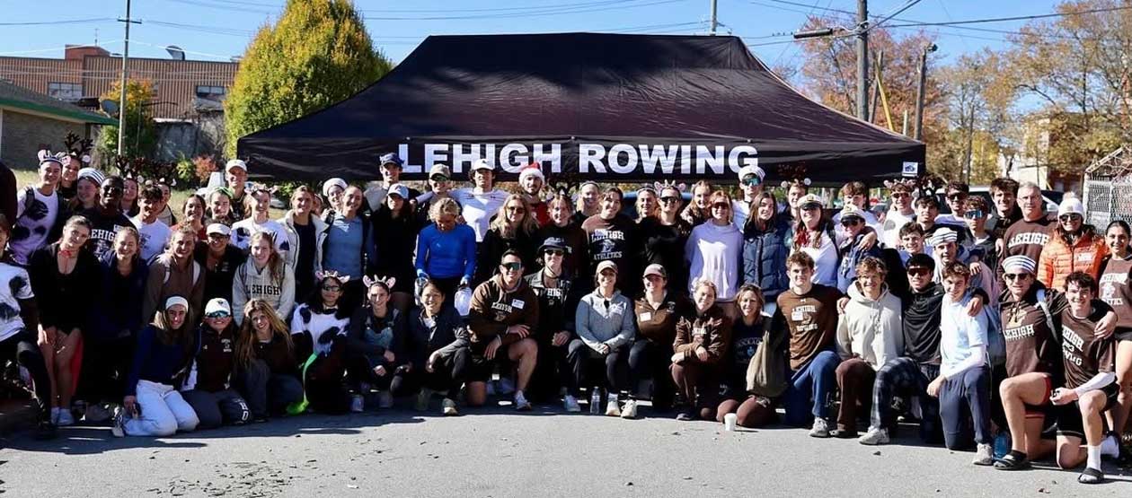 large group of people pose for a group photo infront of a "Lehigh Rowing" banner